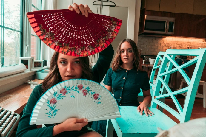 woman in black long sleeve shirt holding white and red floral hand fan